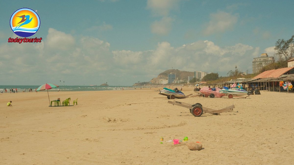 Serene sandy beach with colorful parasol and beached boats, under clea