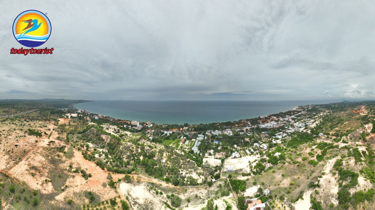 Expansive aerial view of a coastal town overlooking the sea under an o