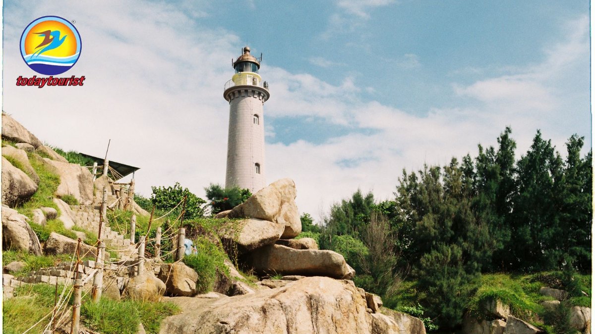 A picturesque lighthouse stands tall on a rocky cliff under a clear bl